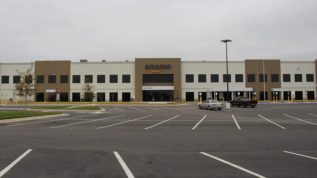 The exterior of a large Amazon fulfilment centre building with a car park in front
