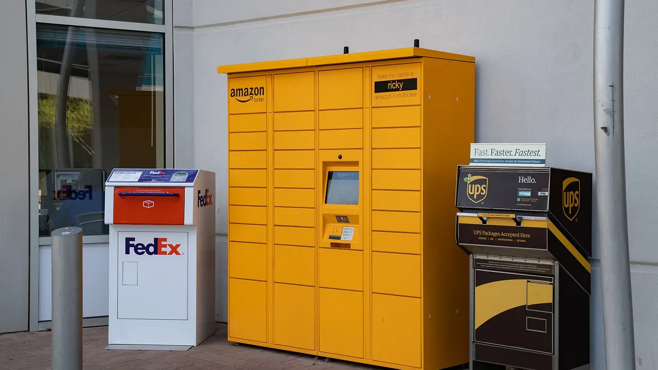 Yellow Amazon parcel lockers beside a white FedEx drop box and a UPS drop box with a 'Fast. Faster. Fastest.' sign on a building exterior.